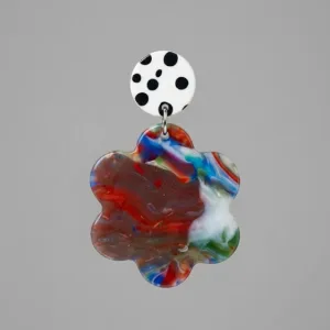 Close-up of floral earrings with a white black polka dot stud and a multicolor marbled flower-shaped drop on a light grey background.